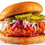 Spicy chicken sandwich with coleslaw and pickles on a brioche bun with copy space